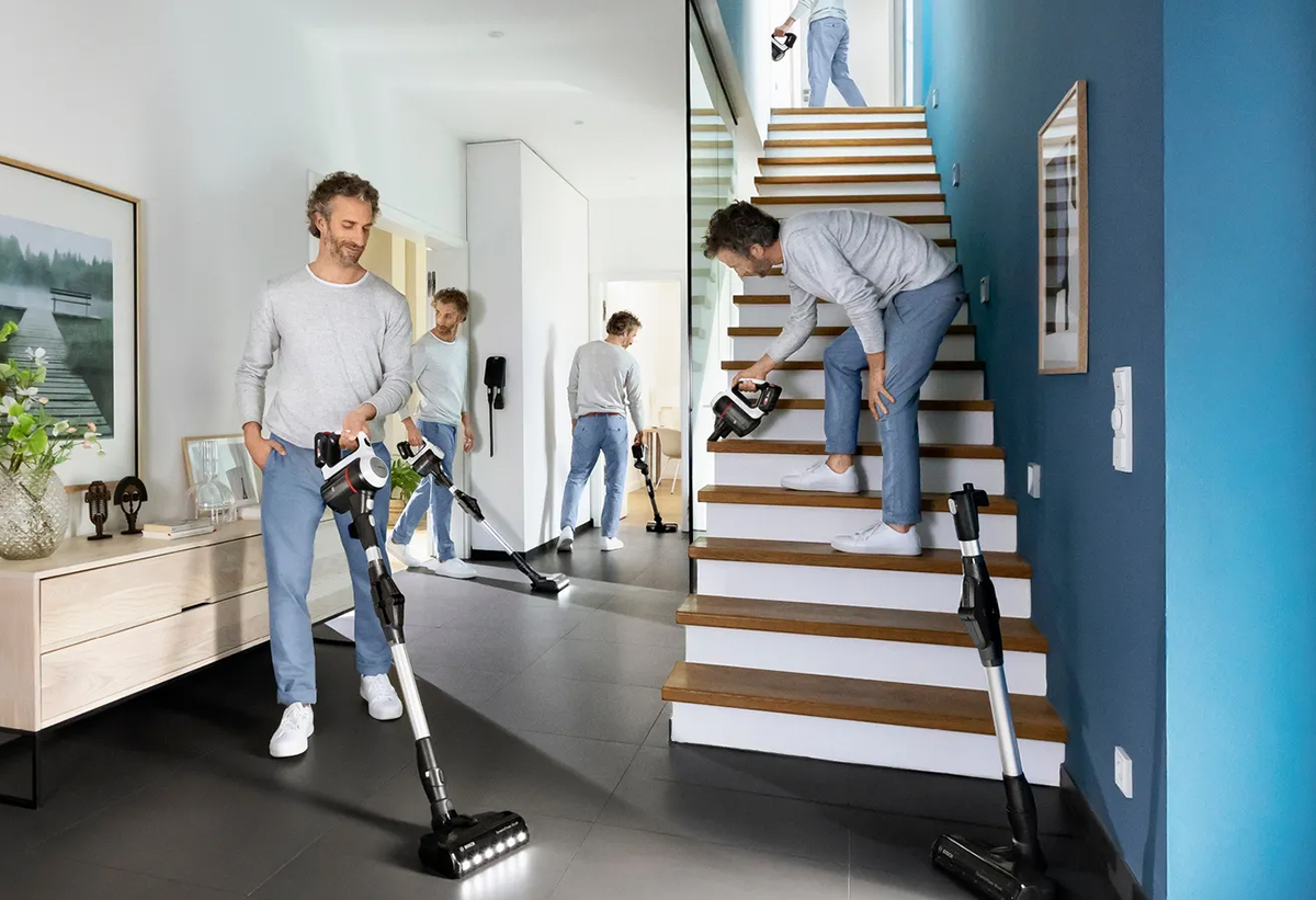 Άνδρας που χρησιμοποιεί σκούπα Bosch για καθαρισμό διαφόρων σημείων σε διάδρομο και σκάλα